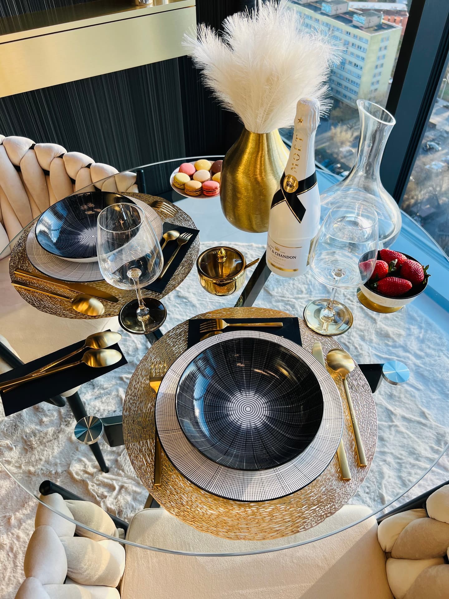 Overhead view of set table with black plates, gold cutlery and macarons