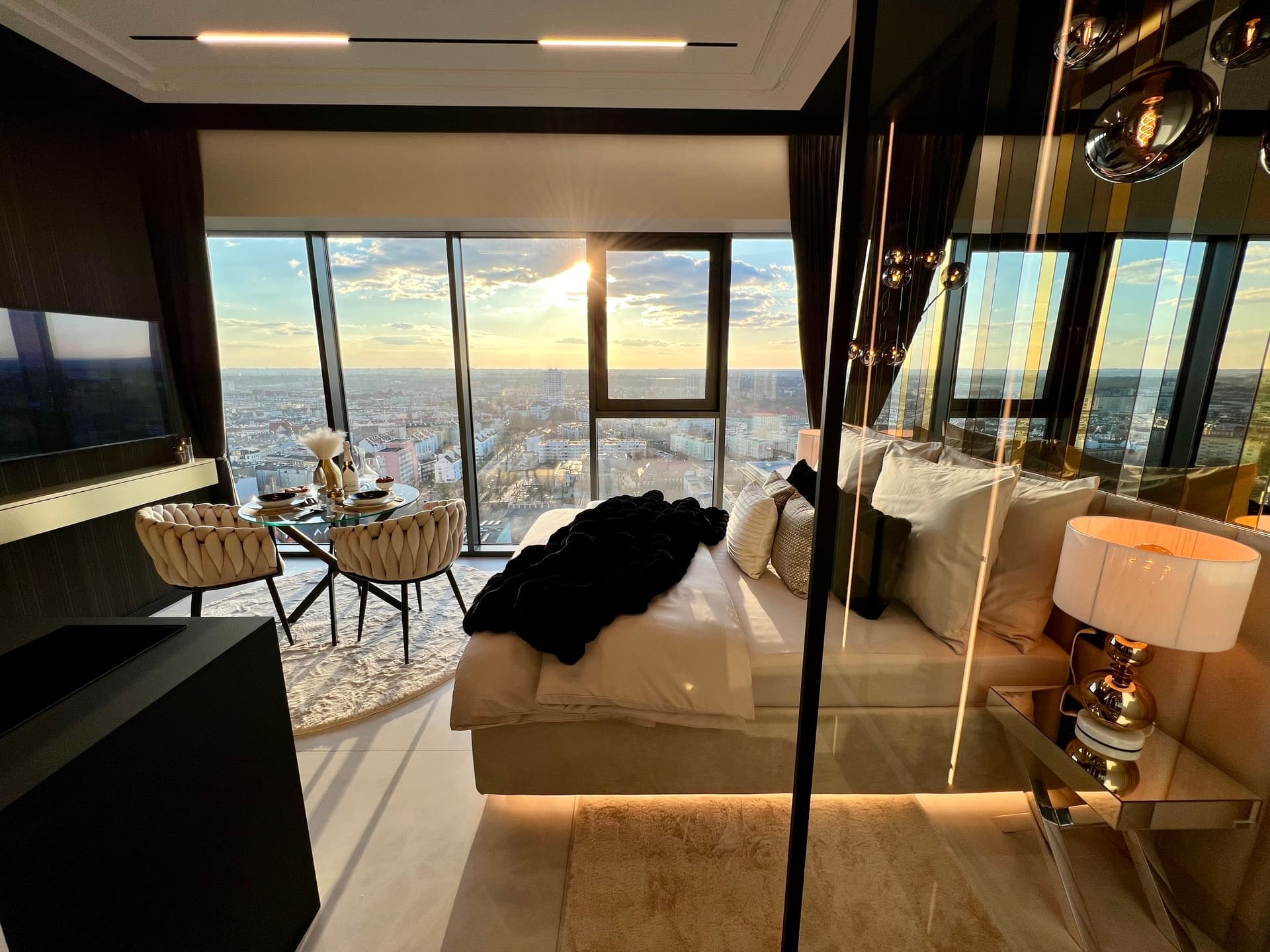 Full suite overview with bed, dining area and sun streaming through windows