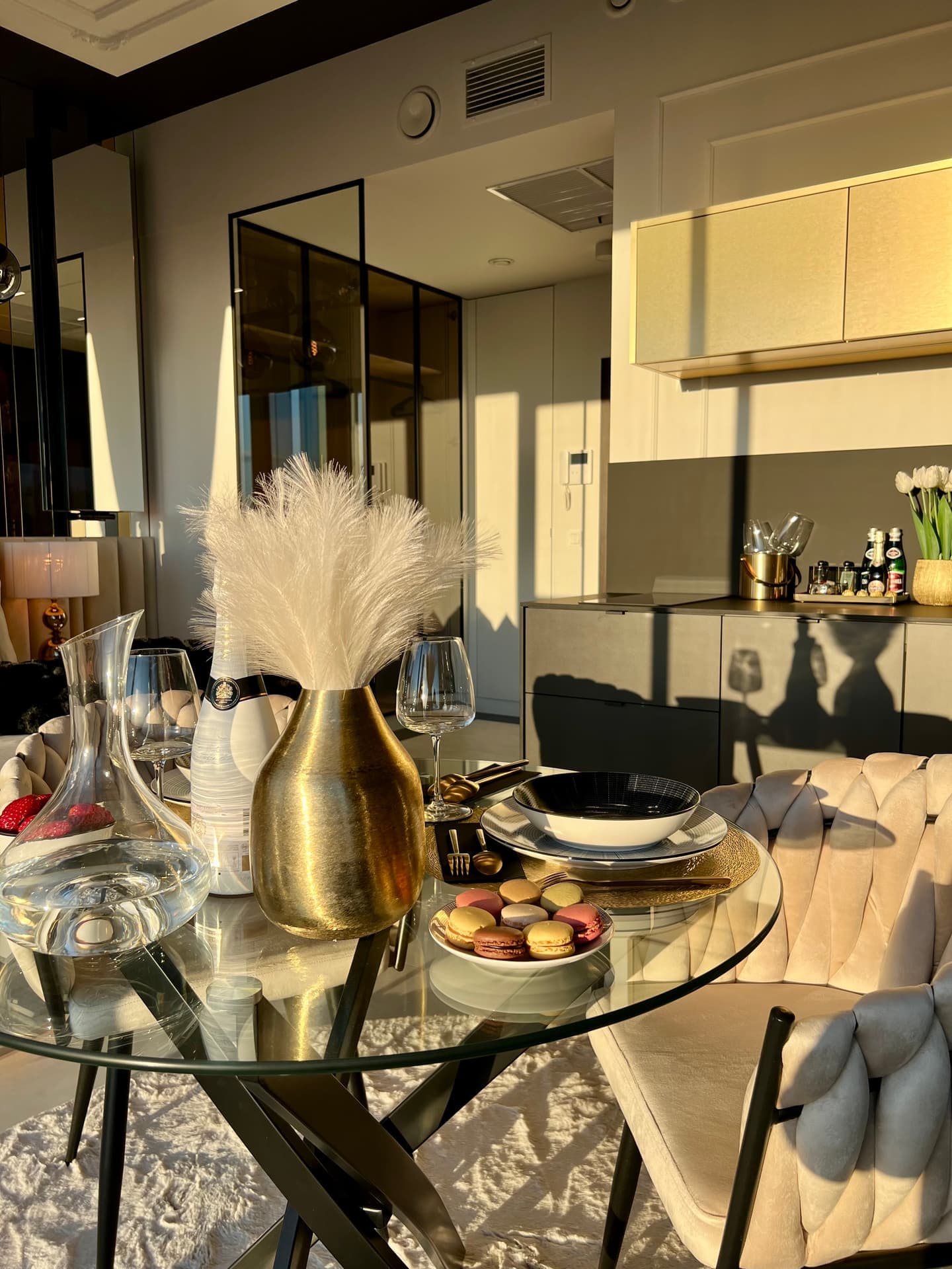 Dining table close-up with macarons, gold vase and kitchenette in background