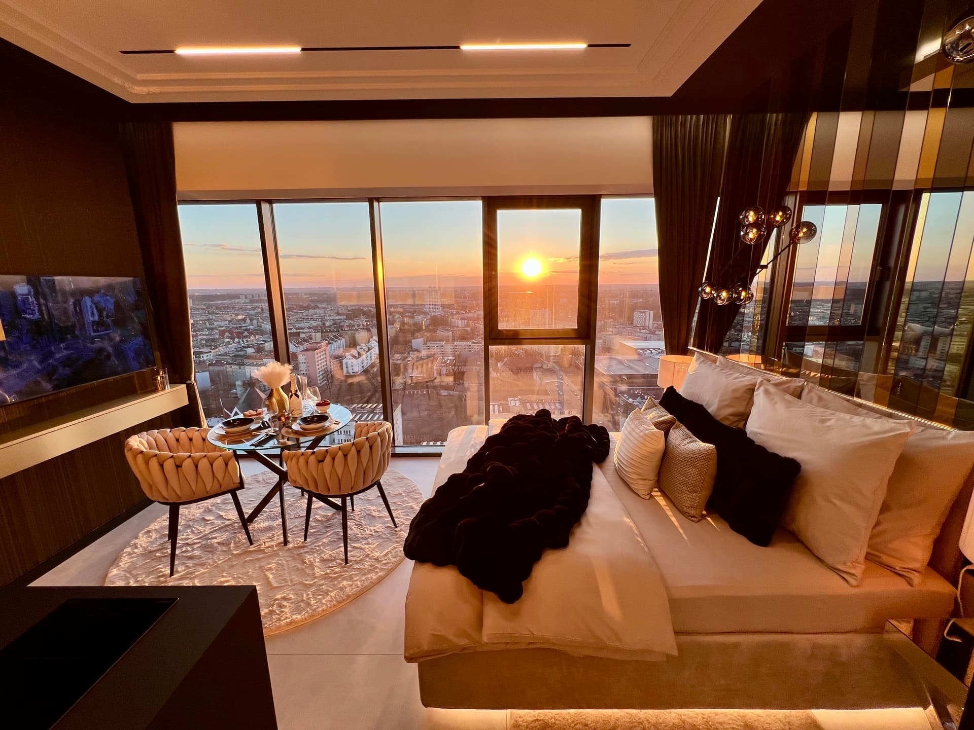 Suite flooded with golden sunset light through panoramic windows