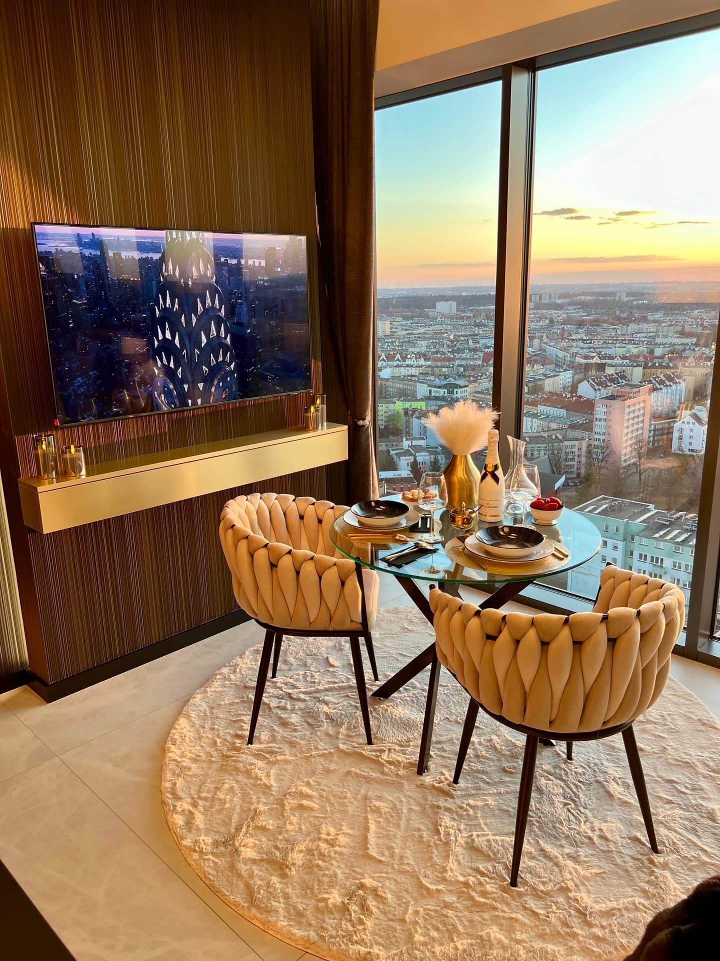 Dining corner with glass table, wall-mounted TV and sunset panorama