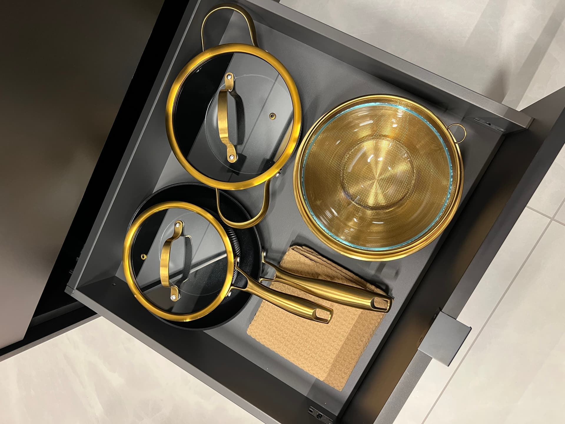 Kitchen drawer with gold pans, glass lids and colander
