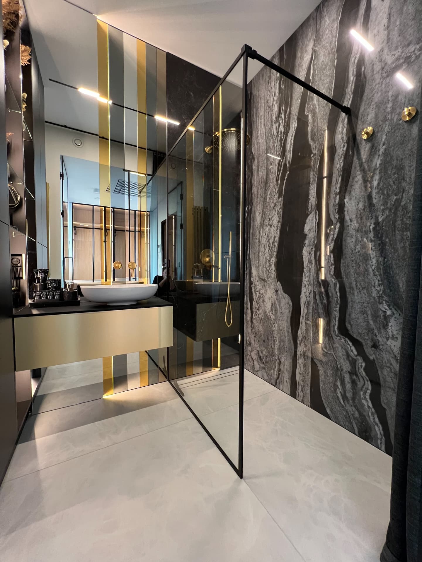Bathroom with grey marble wall, walk-in shower and gold fixtures