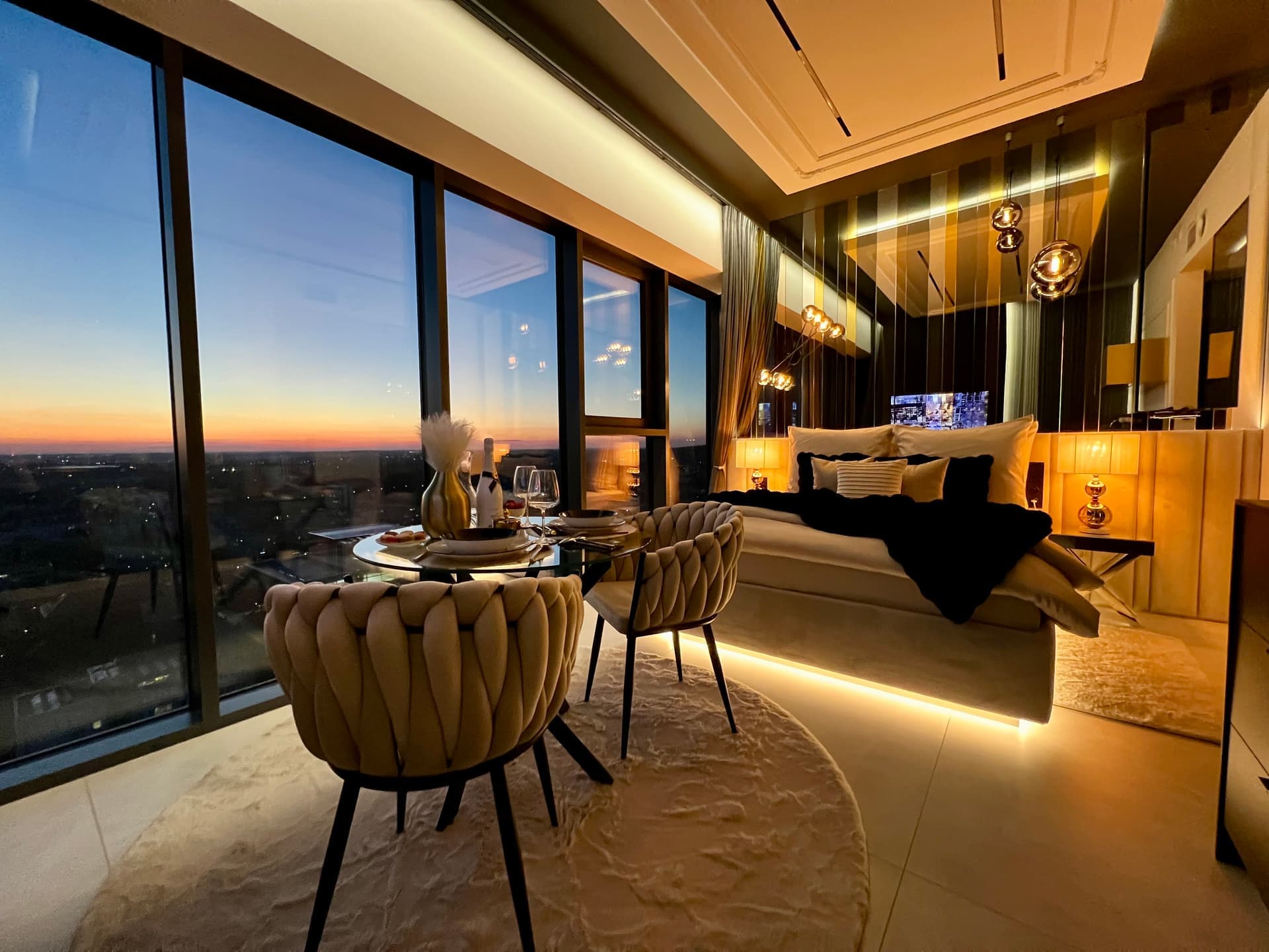 Suite with elegant dining area, bed and panoramic twilight view